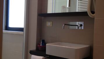Une salle de bain avec un lavabo blanc, un miroir, un porte-serviettes et une fenêtre.