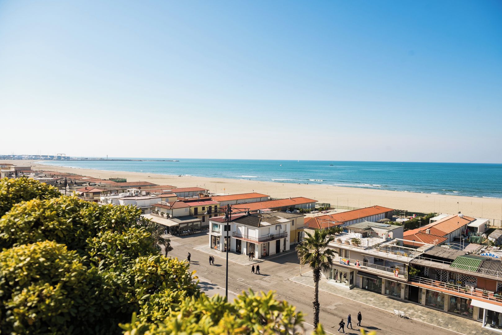 A coastal town with buildings, a beach, and a clear sky.