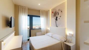 A hotel room with a bed, bedside table, and a television.