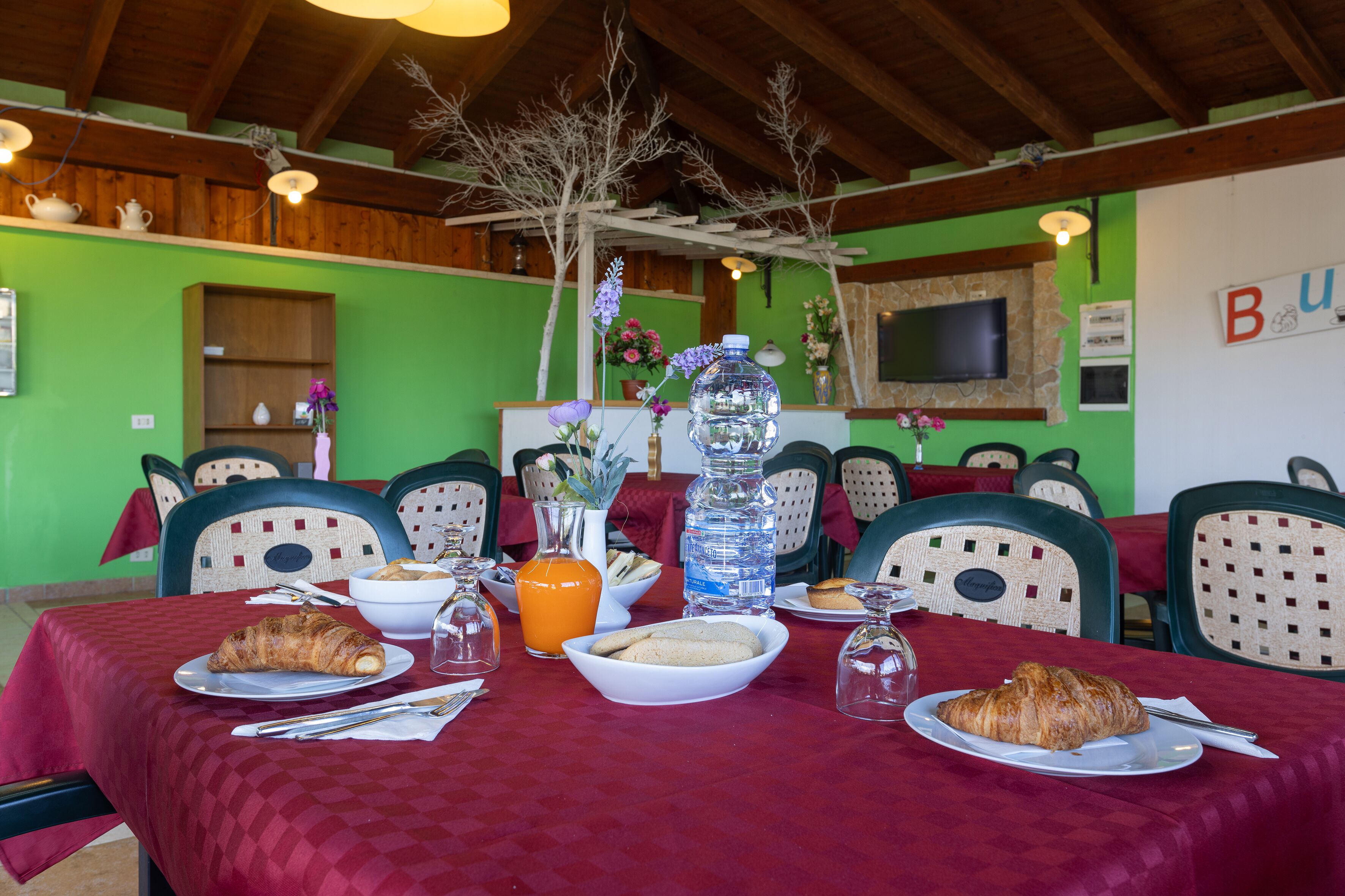 A dining area with a table set for breakfast, including croissants, a bowl of cookies, and a bottle of orange juice.
