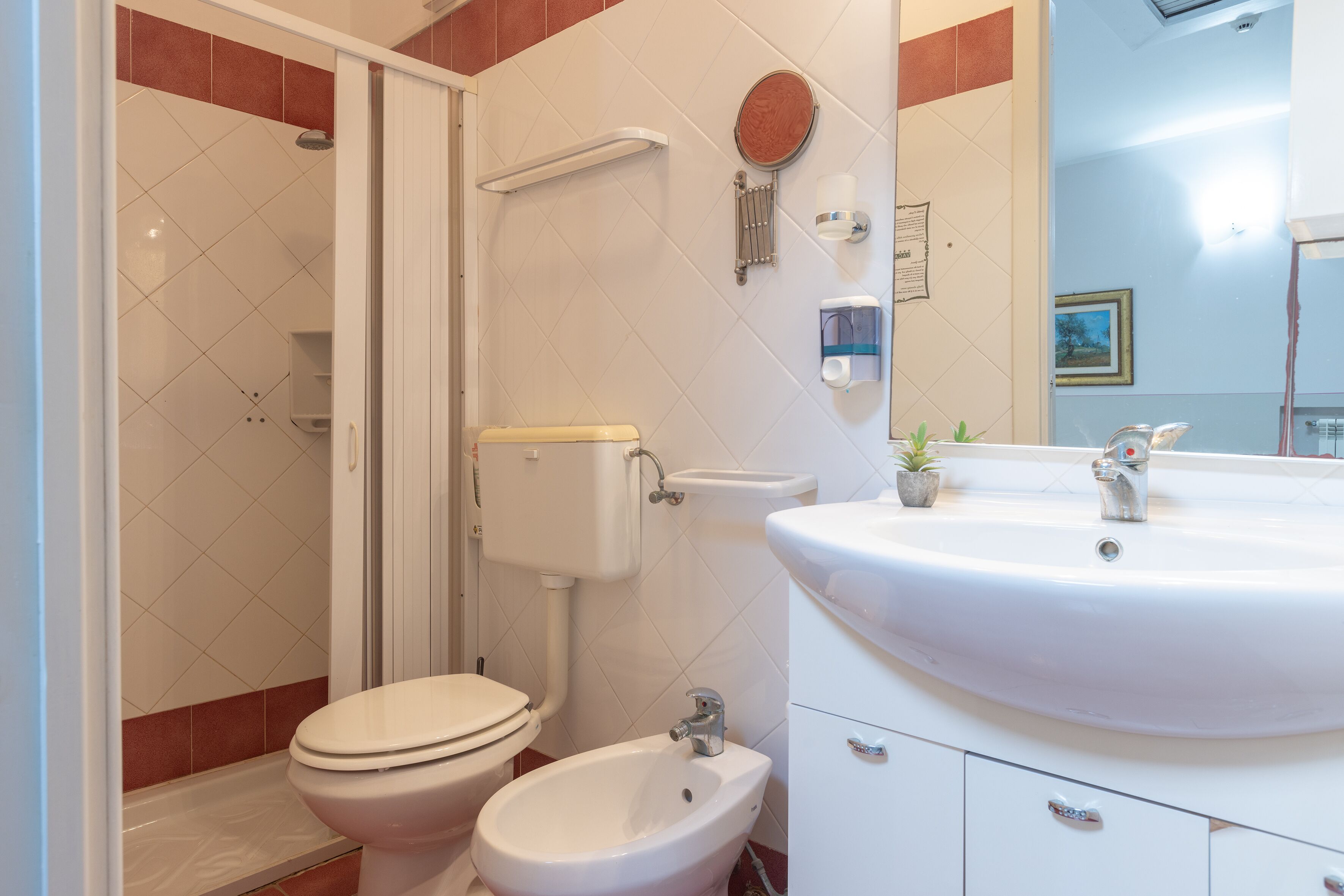 Une salle de bain comprenant des toilettes, un bidet, un lavabo et une douche.