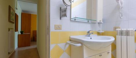 A bathroom with a sink, mirror, and towel rack.