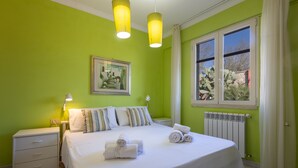 Ein Schlafzimmer mit einem großen Bett, zwei Nachttischlampen, einem gerahmten Bild an der Wand und einem Fenster mit Vorhängen.