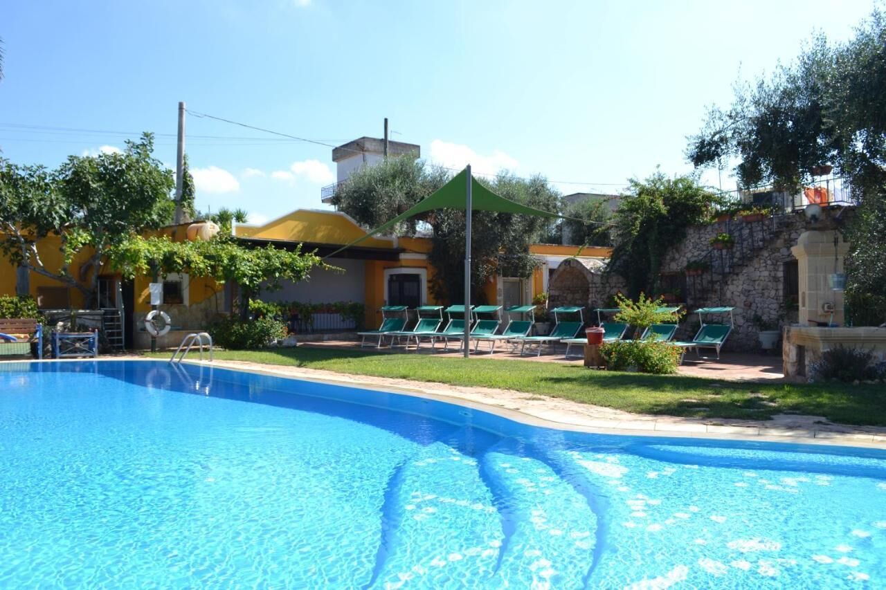 Une piscine avec des chaises longues vertes et un mur de pierre en arrière-plan.