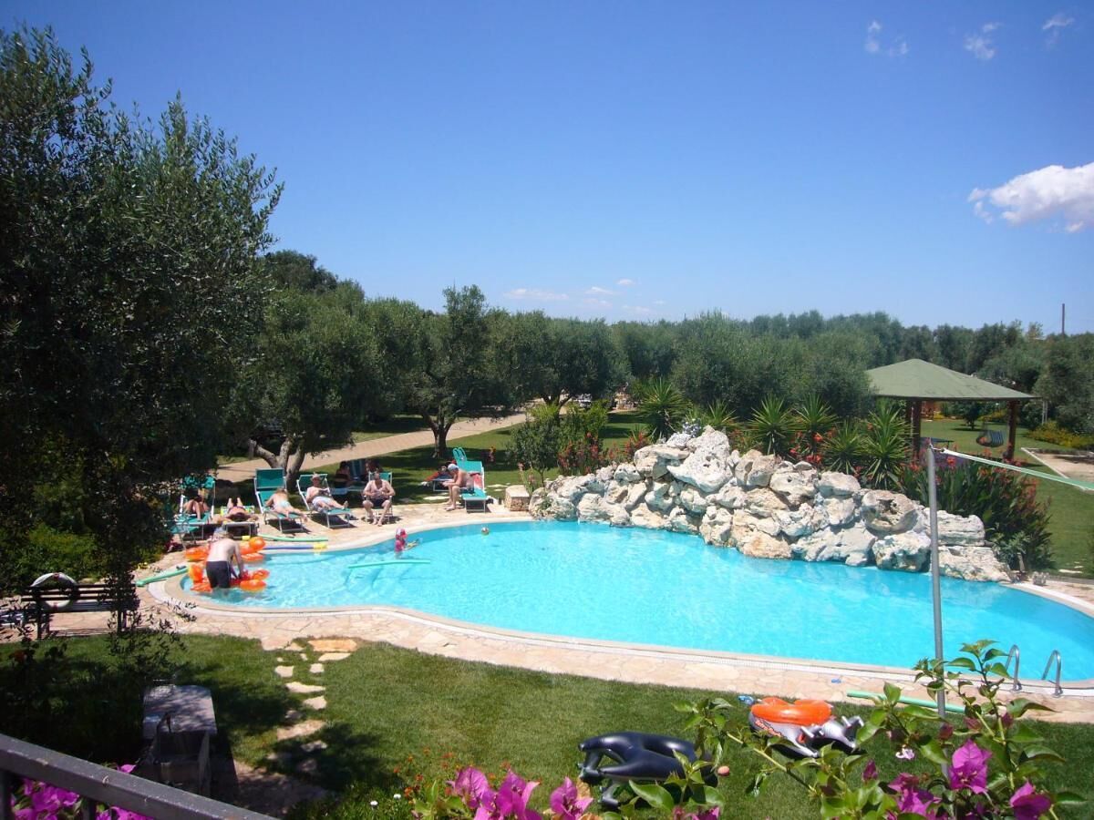 Une piscine agrémentée d’un élément rocheux, entourée de verdure et dotée d’un belvédère.