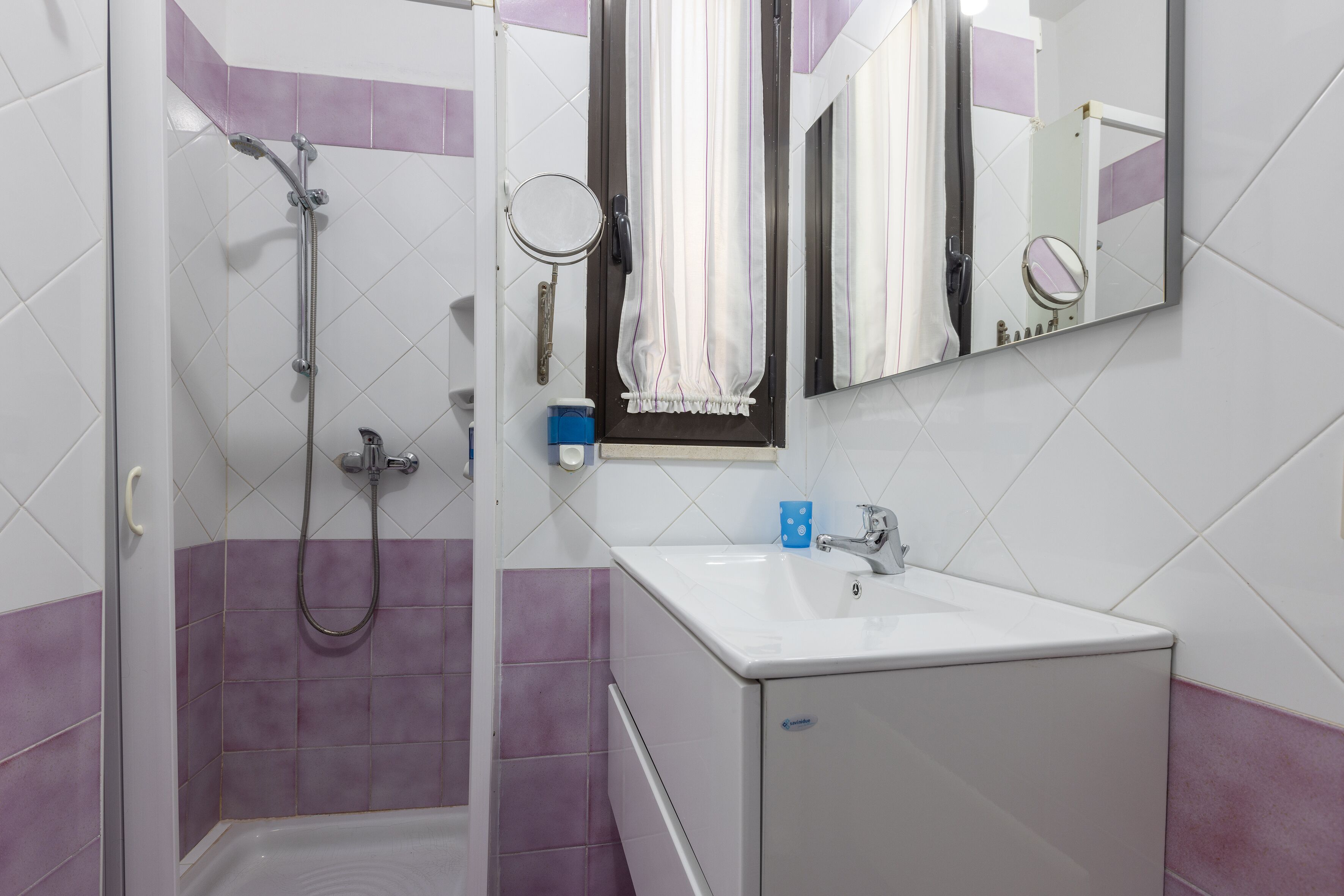A bathroom with a shower, a sink, and a mirror.