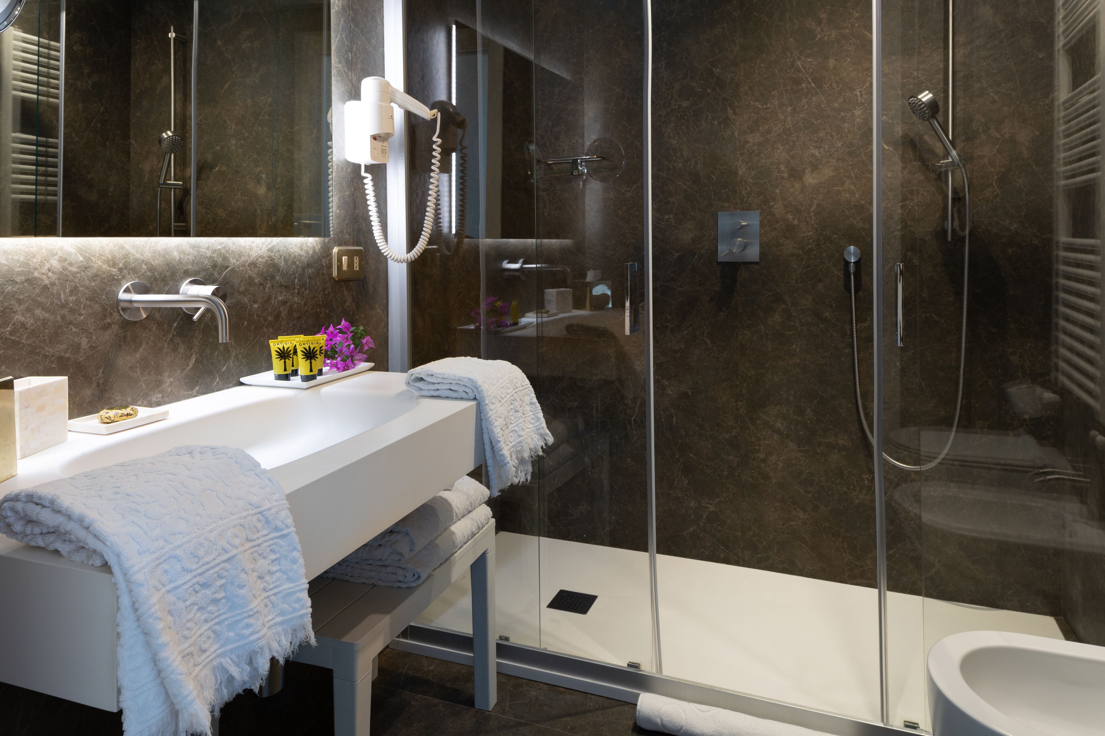 Un baño moderno con ducha envuelta en vidrio, un lavabo blanco y un espejo grande.