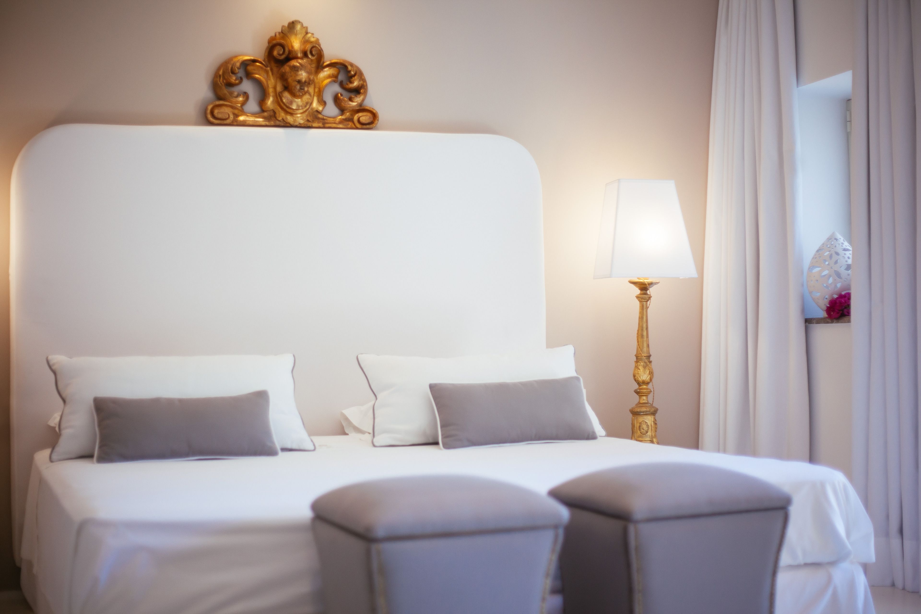A hotel room with a large bed, two bedside tables, a lamp, and a decorative headboard.