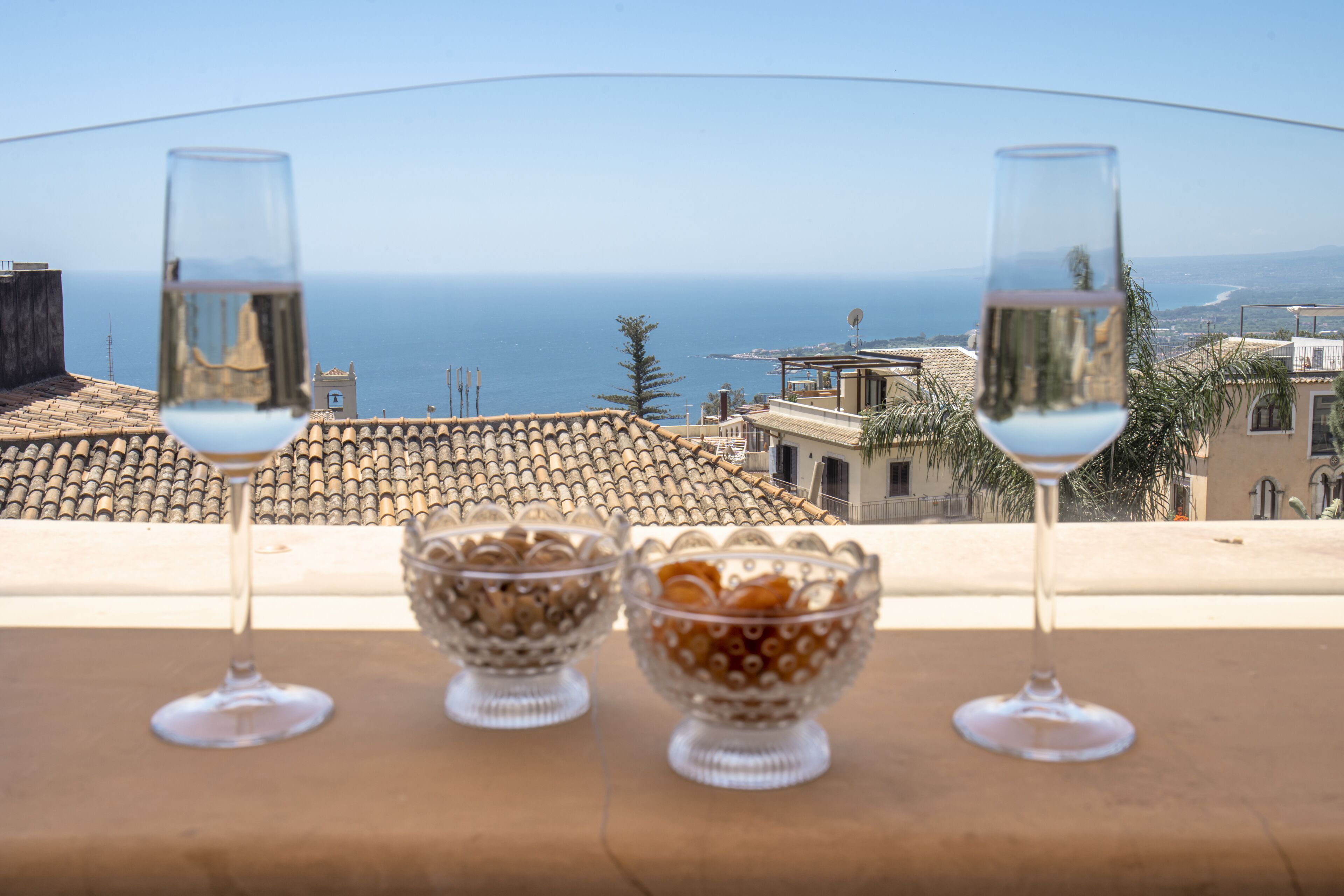 Two glasses of water and two bowls on a balcony overlooking a coastal cityscape.