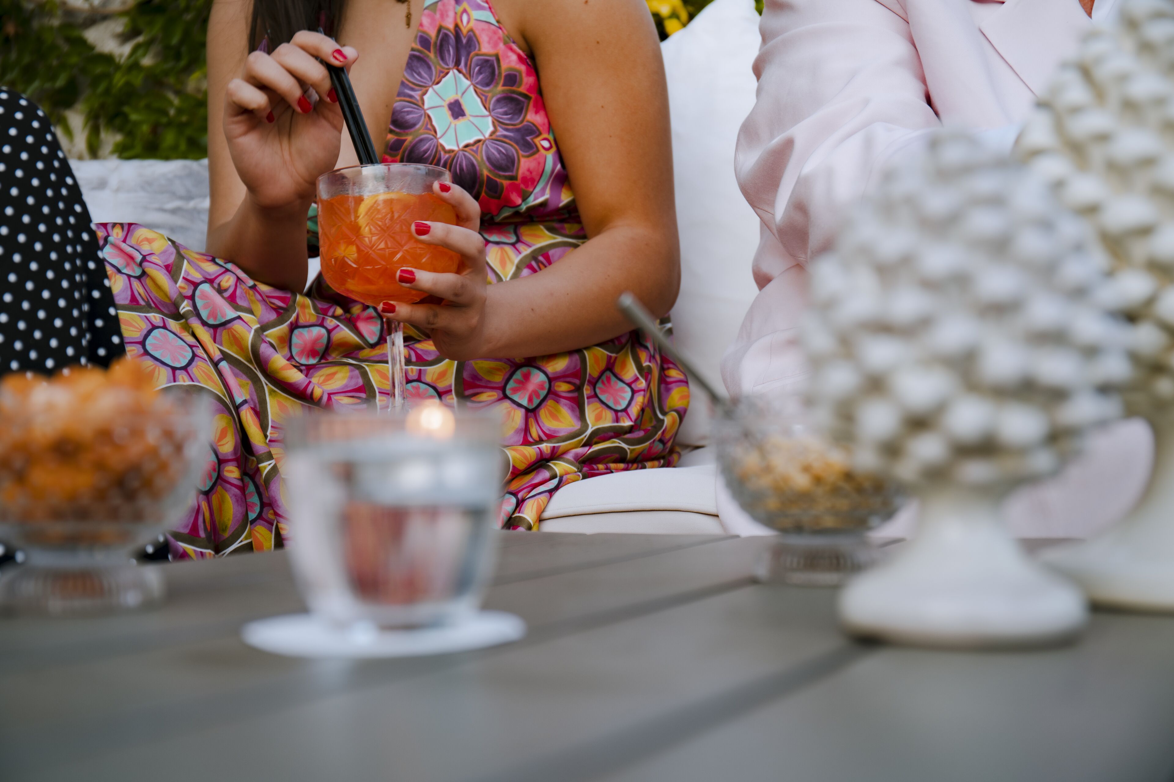 Una persona sentada a una mesa con una bebida, rodeada de varios platos y una vela.
