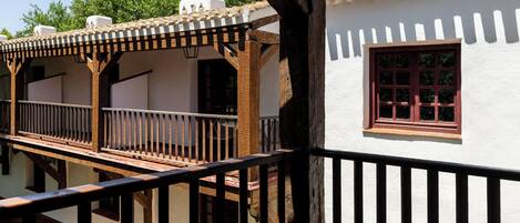 A traditional building with a balcony, wooden beams, and a red window.