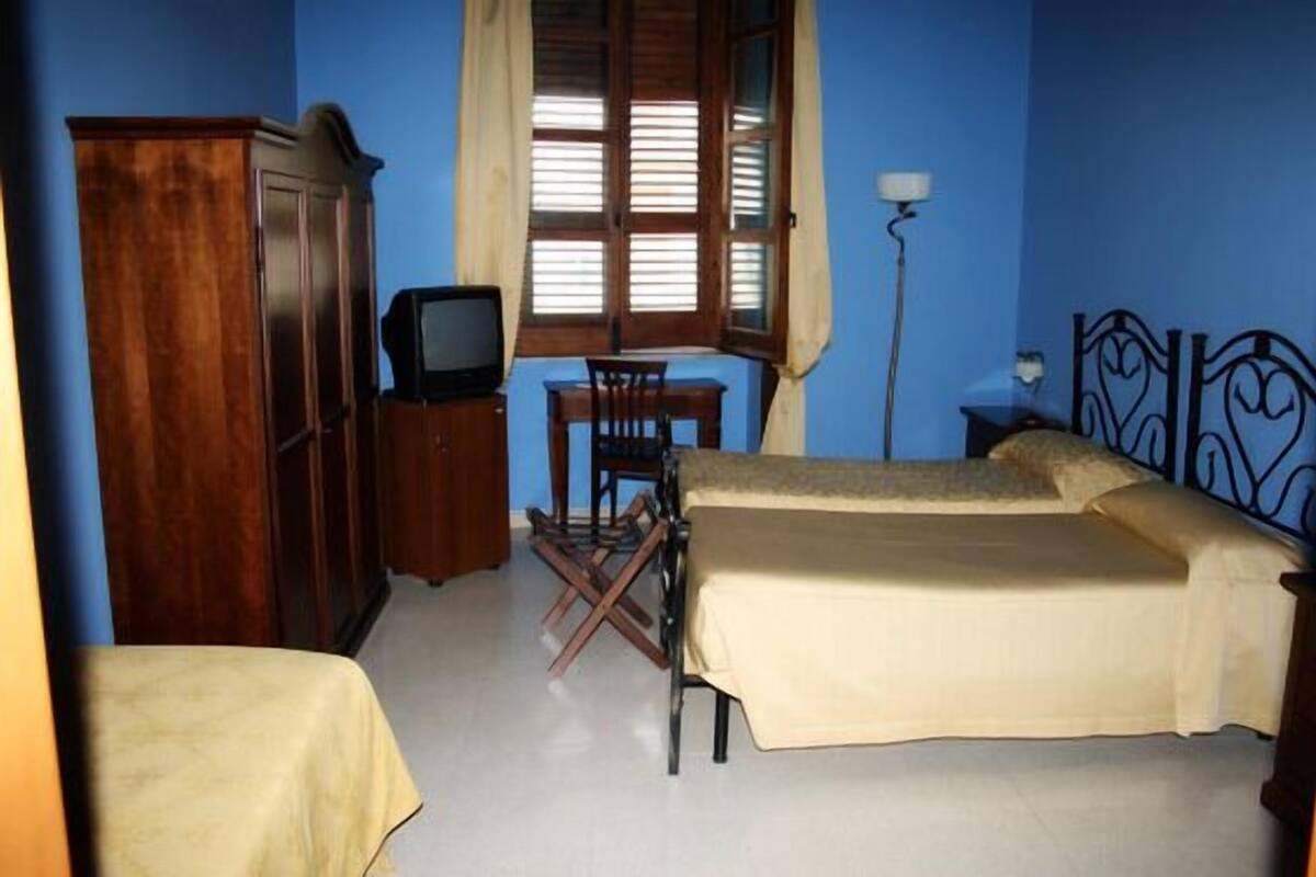 Ein Schlafzimmer mit zwei Betten, einem Schreibtisch, einem Fernseher und einem Kleiderschrank.