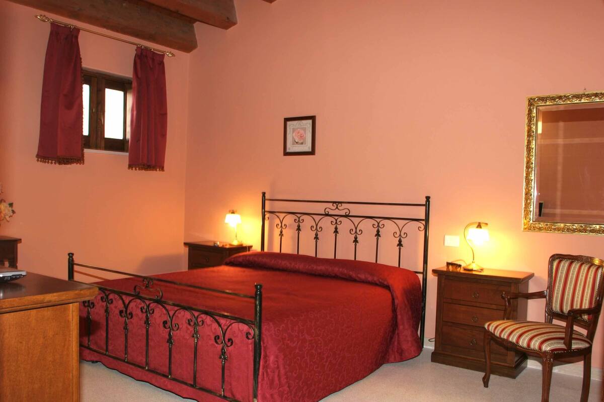 Ein Schlafzimmer mit einem Metallbettgestell, einer Holzkommode, einem Stuhl und zwei Nachttischen mit Lampen.