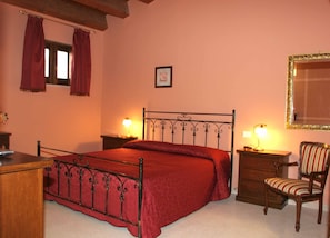 A bedroom with a metal bed frame, a wooden dresser, a chair, and two bedside tables with lamps.