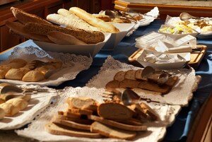 Una mesa de buffet con panes, pasteles y cubiertos diversos.