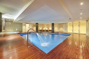 Una piscina cubierta, una piscina al aire libre, sombrillas, tumbonas