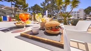 Una mesa con una hamburguesa, una bebida y una cesta de papas fritas.