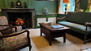 Un salón tradicional con chimenea, paredes verdes y muebles clásicos.