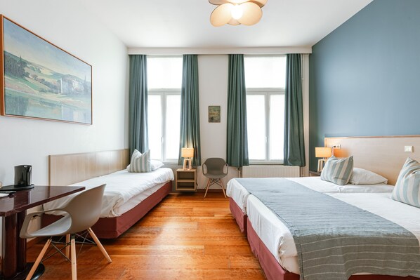 A hotel room with two beds, a desk, a chair, a lamp, and a painting on the wall. - Malleberg (Bruges)