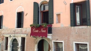 Un edificio con múltiples ventanas, algunas con contraventanas, y un cartel que dice "Corte Nova".
