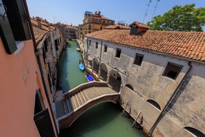 A narrow canal with buildings on either side, a bridge, and a boat. - Corte Nova (Venice)
