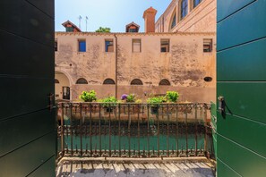 A courtyard with a metal gate, a building with arched windows, and a green door. - Corte Nova (Venice)