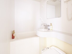 A modern bathroom with a white sink, a mirror, and a handheld showerhead. - KOKO HOTEL Korakuen (Tokyo)