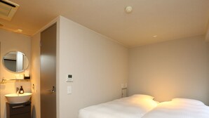 A bedroom with a bed, a bedside table, a mirror, a sink, and a thermostat. - KOKO HOTEL Korakuen (Tokyo)