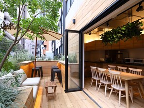 An outdoor patio area with wooden flooring, a seating arrangement, and a view of the cityscape. - KOKO HOTEL Korakuen (Tokyo)
