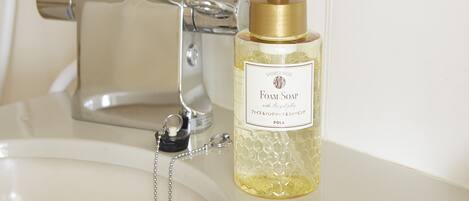 A bathroom sink with a gold pump bottle of foam soap.