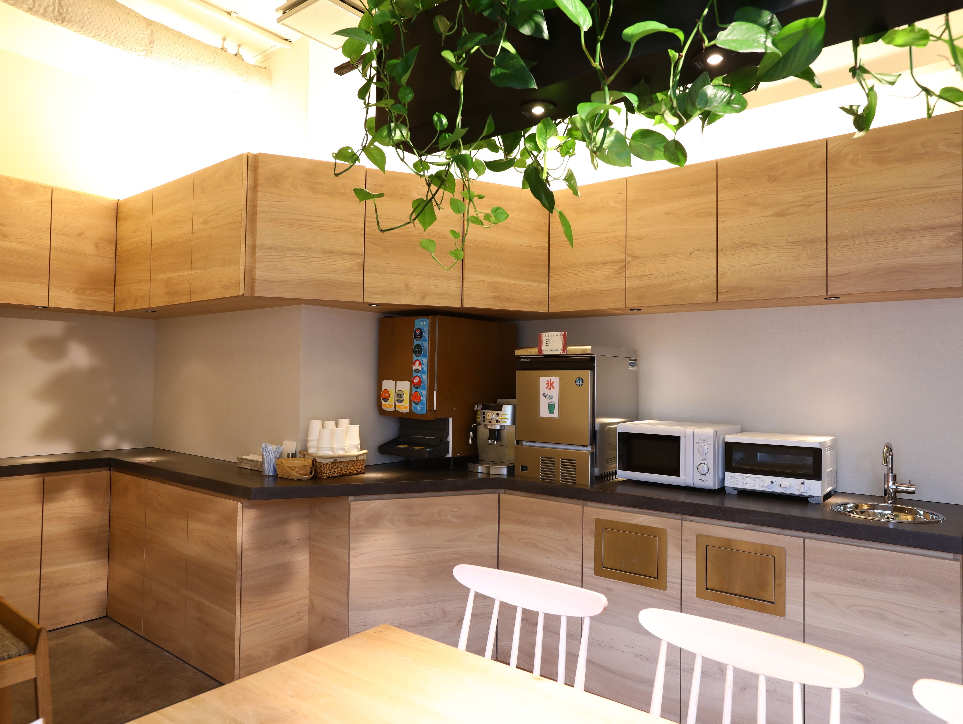 Une cuisine moderne avec des meubles en bois, un four à micro-ondes, un réfrigérateur et un coin bar avec des tabourets.