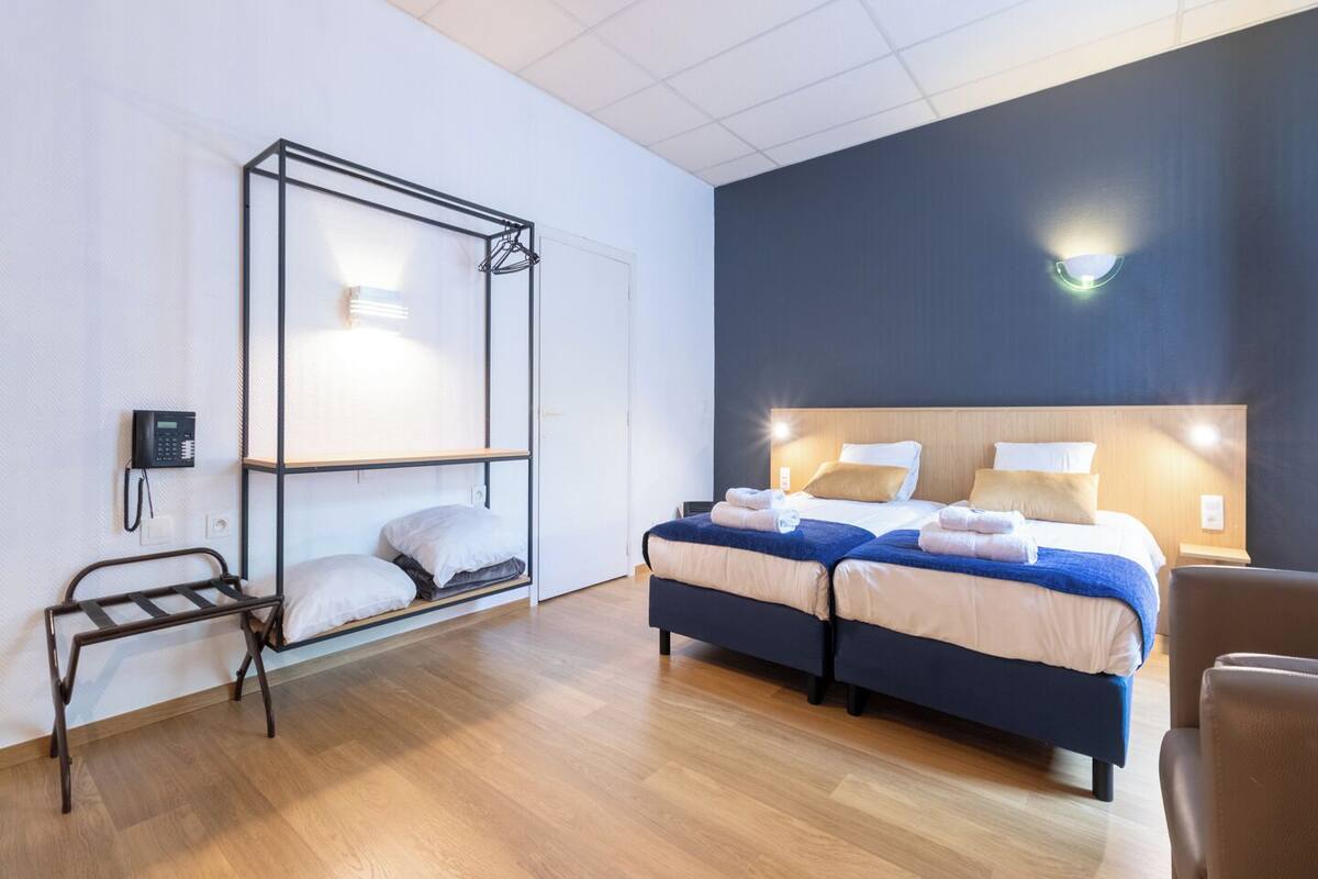 A hotel room with a bunk bed, a desk, a chair, and a bedside table.