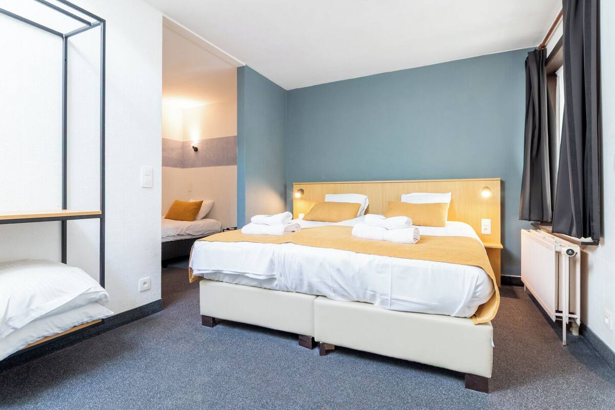 A hotel room with a large bed, a smaller bed, and a desk.
