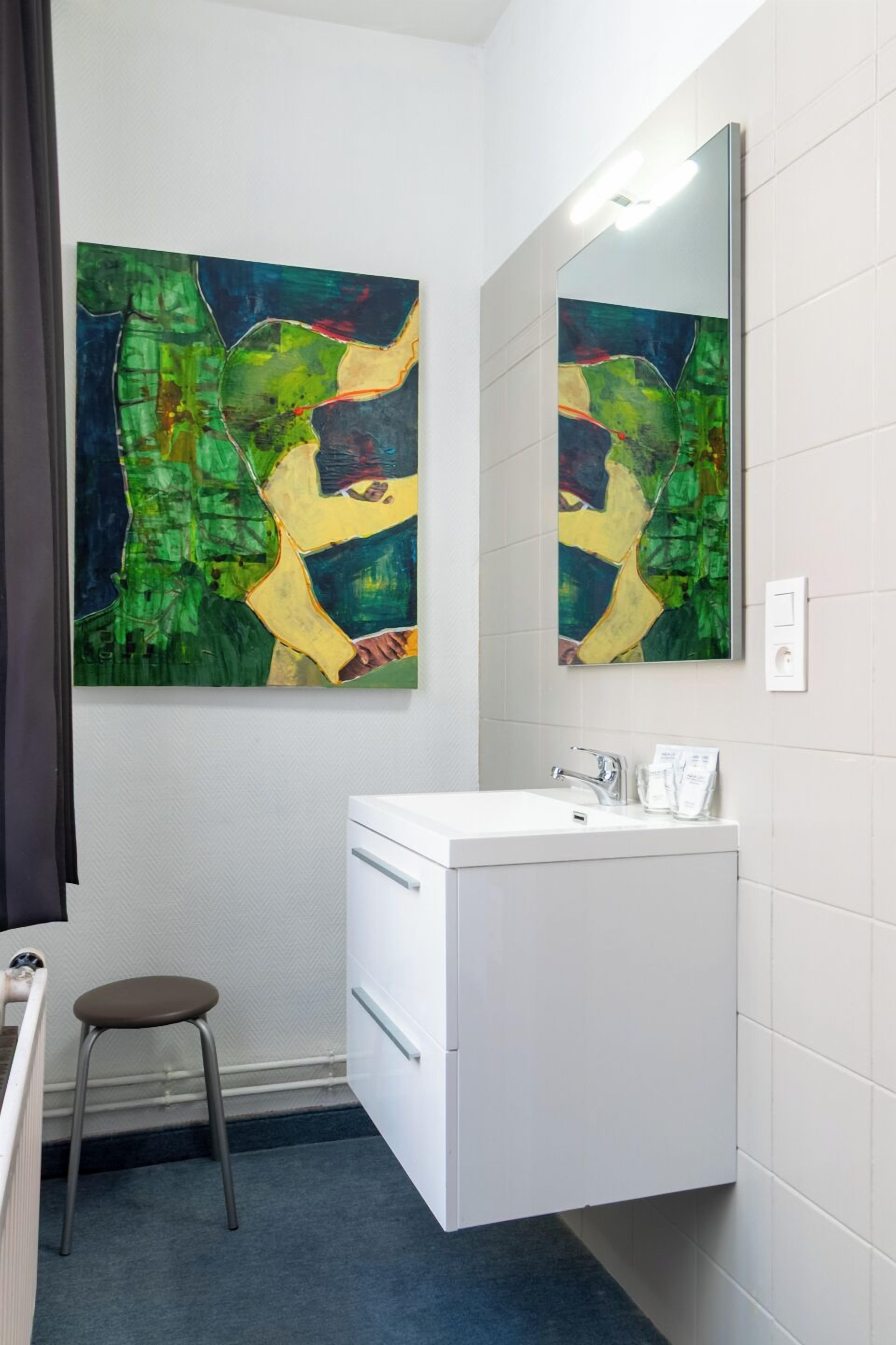 Een badkamer met een wit wastafelmeubel, een spiegel en een kleurrijk abstract schilderij aan de muur.