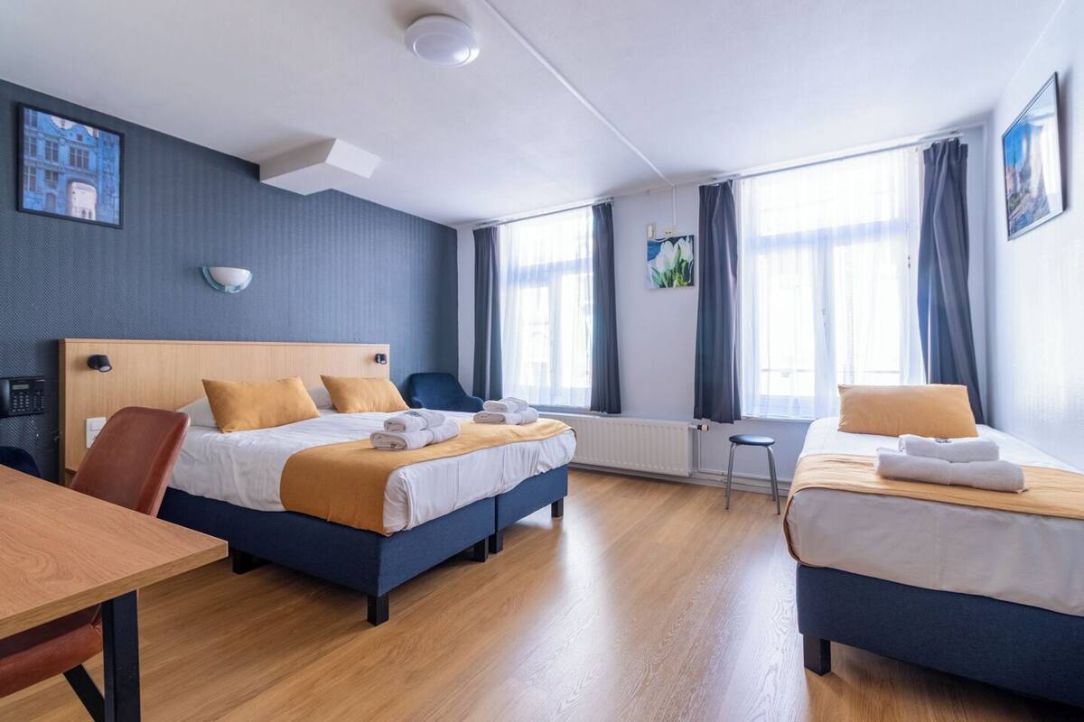A hotel room with two beds, a wooden desk, and a small table.