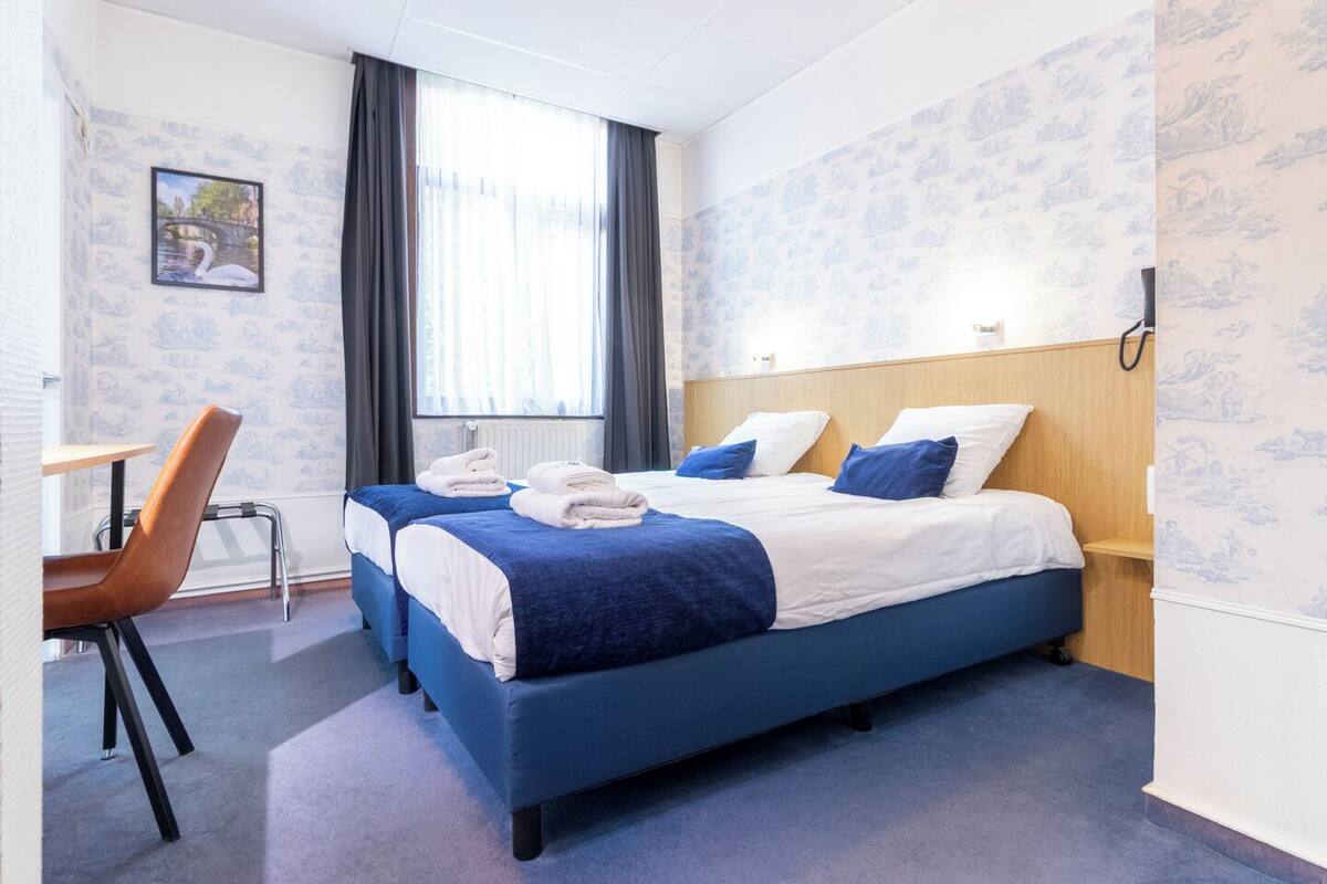 A hotel room with two beds, a desk, and a chair.