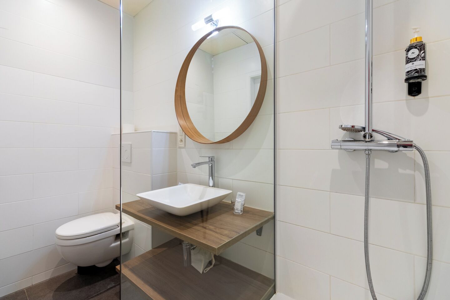 A modern bathroom with a glass-enclosed shower, a white sink, and a toilet.