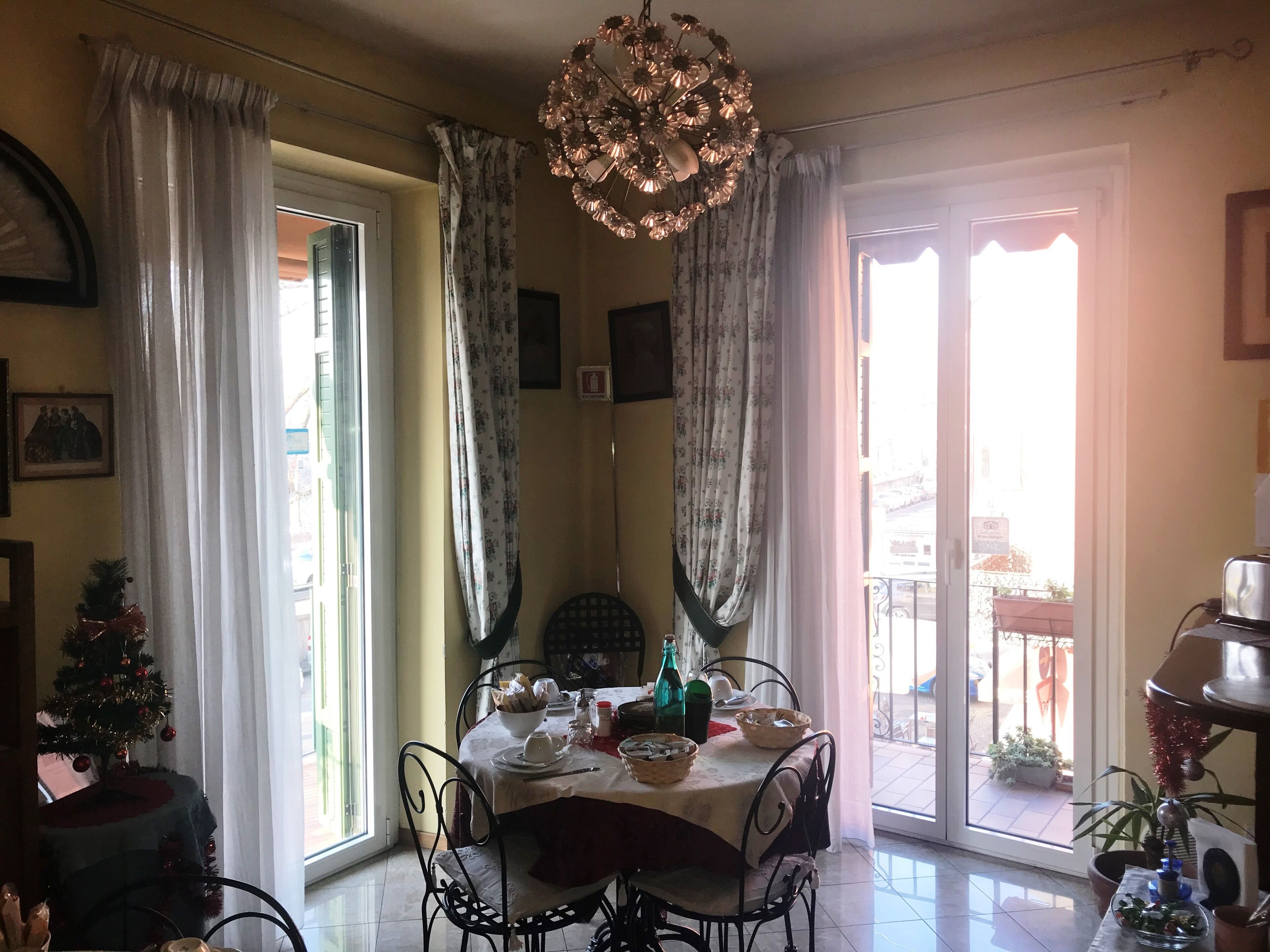 A dining area with a table set for four, a chandelier, and a view of the outside.