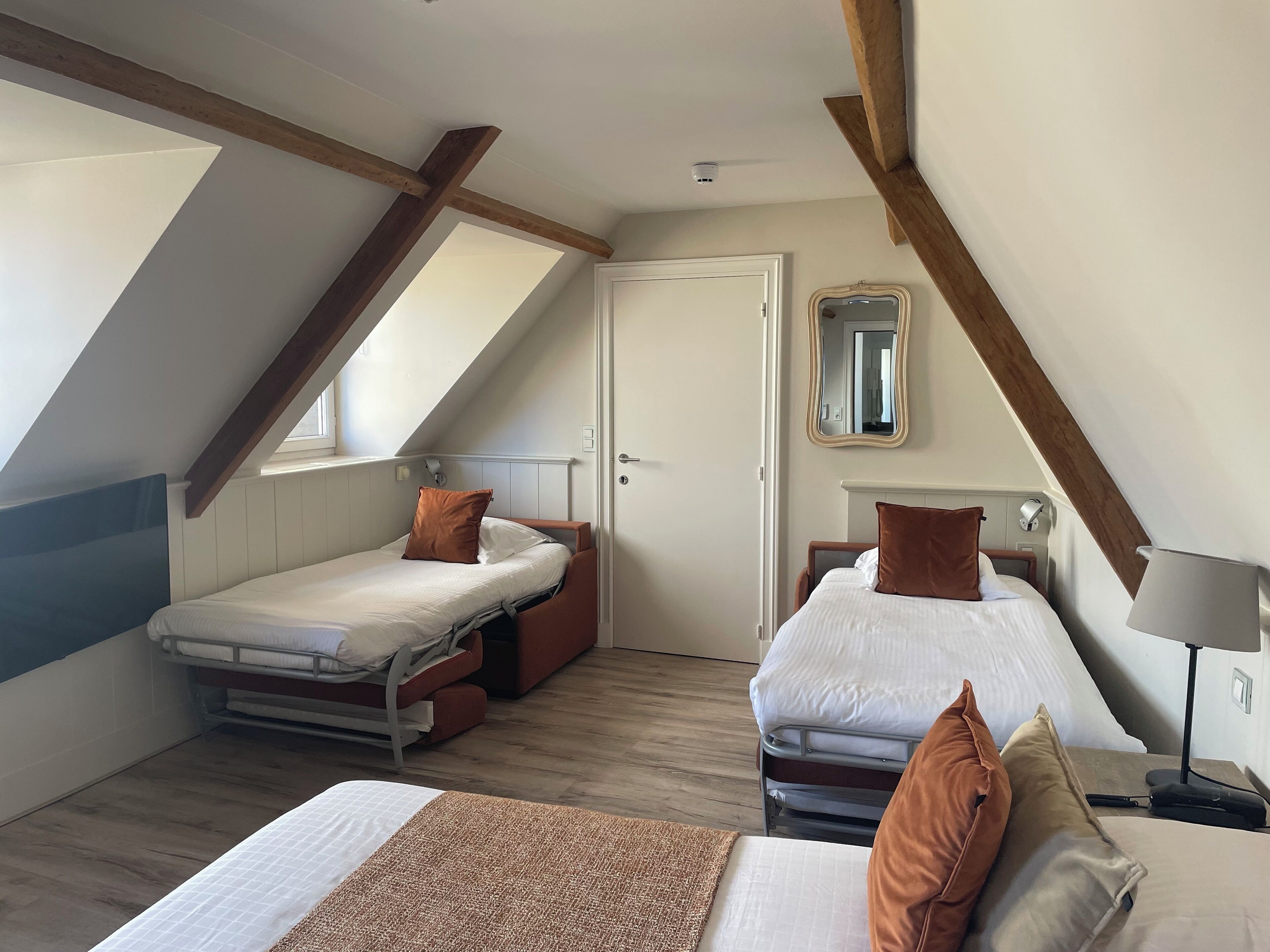 Un dormitorio con dos camas, una ventana, un espejo y un ventilador de techo.