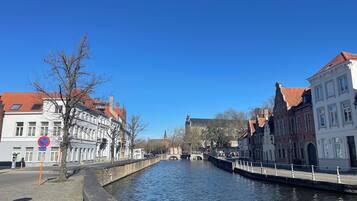 A canal with historic buildings on either side, a no parking sign, and a clear blue sky.