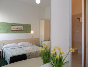 Ein Hotelzimmer mit Bett, Nachttisch, Spiegel und einem Wandbild.