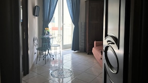 A room with a dining area, a sofa, and a view through a large window. - B&B Art Suite Principe Umberto (Naples)