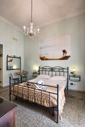 A bedroom with a bed, a chandelier, a painting, a mirror, and bedside tables. - B&B Art Suite Principe Umberto (Naples)