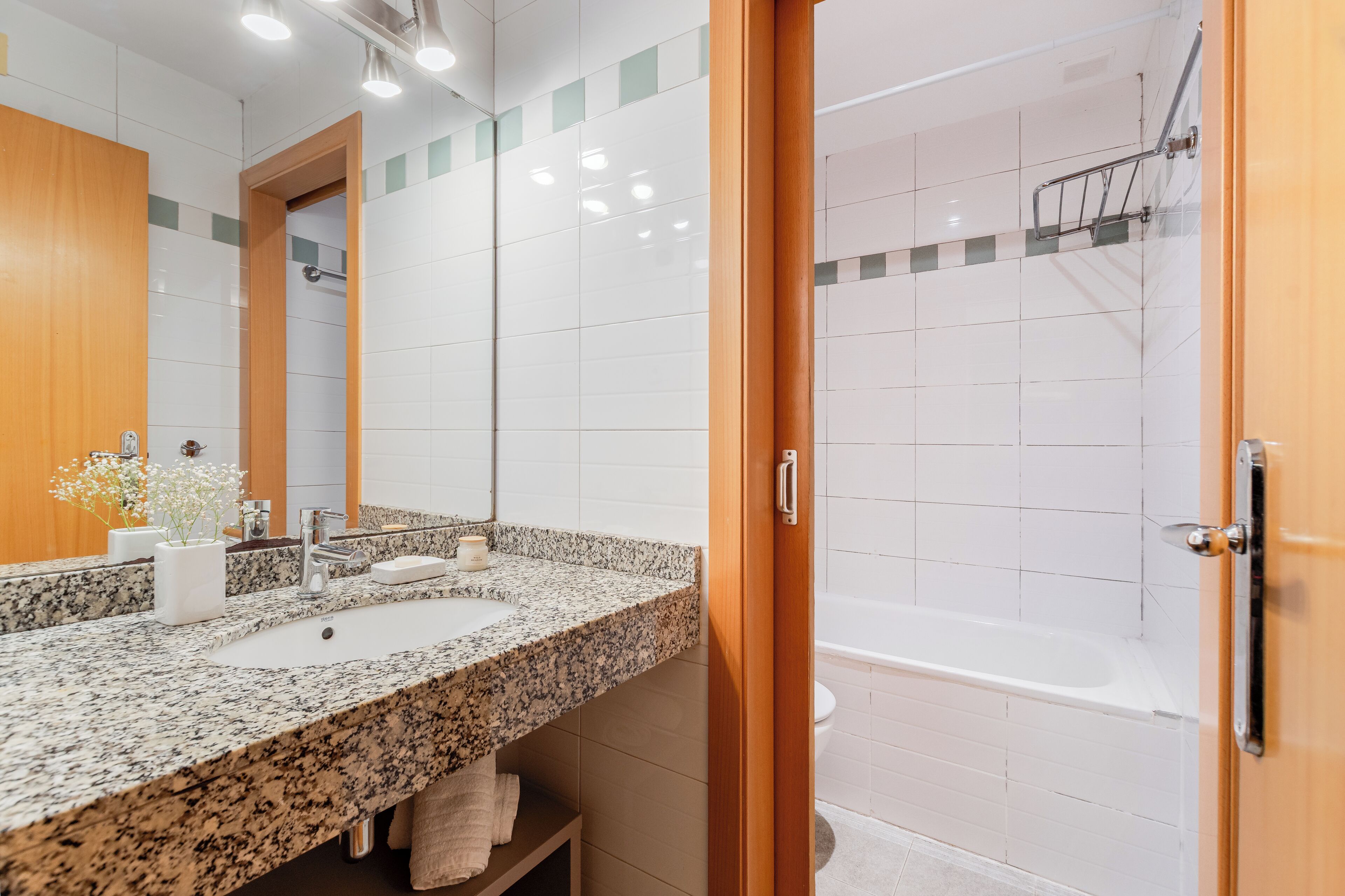 A modern bathroom with a granite countertop sink, a large mirror, and a walk-in shower.