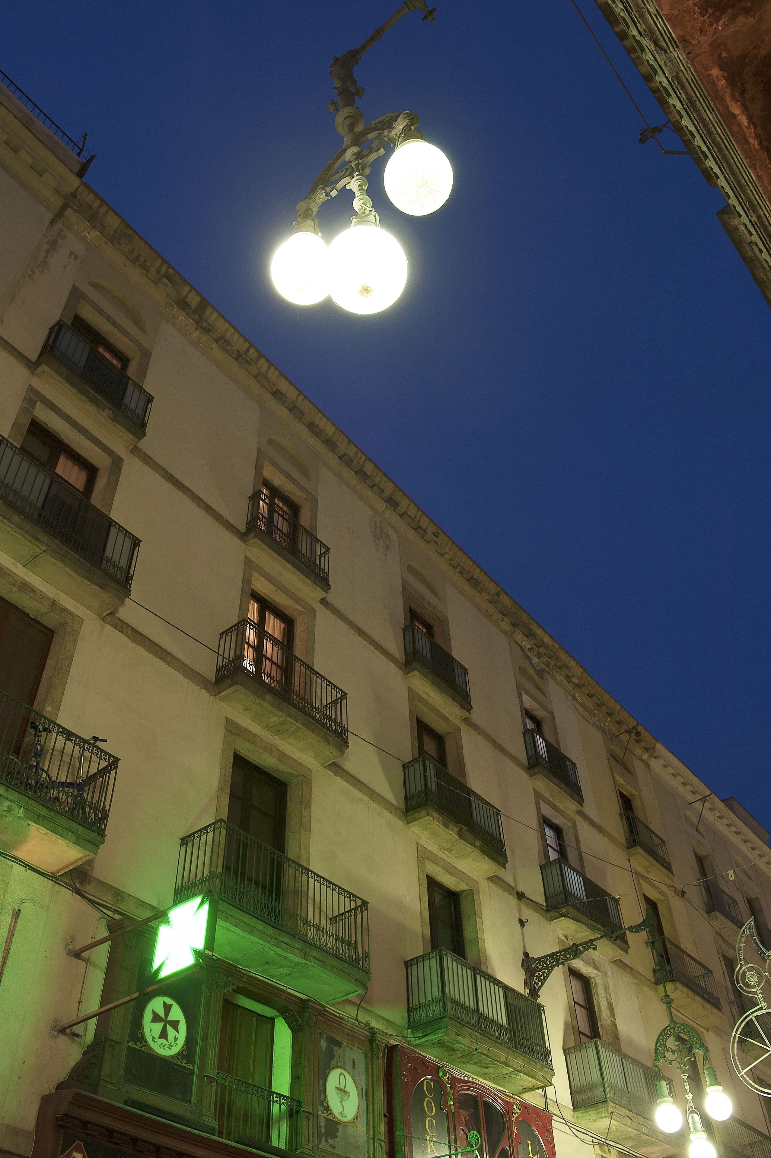 A multi-story building with balconies, a green arrow sign, and a clock.
