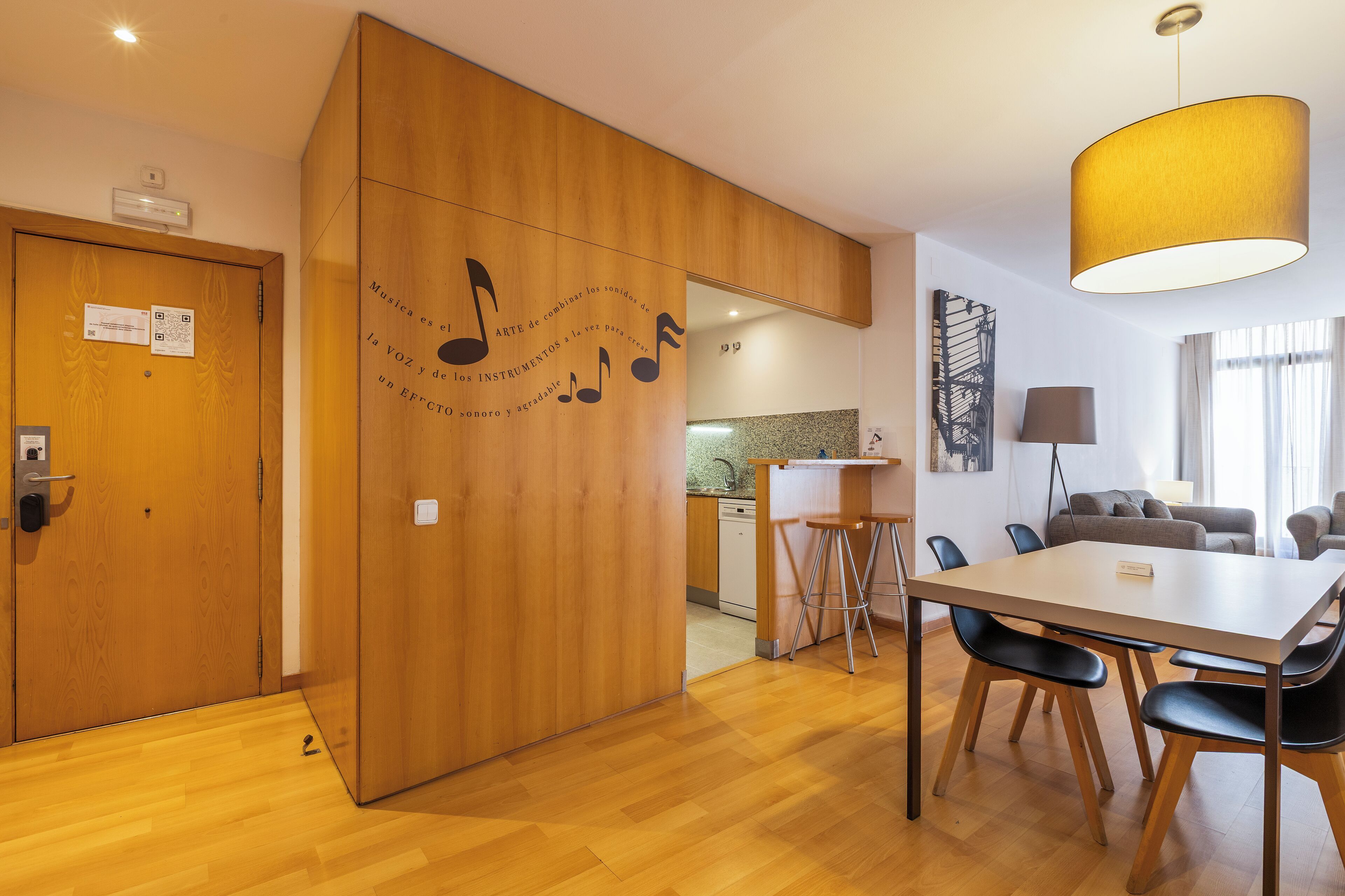 A modern kitchen with wooden cabinets, a dining area with a table and chairs, and a large window with curtains.