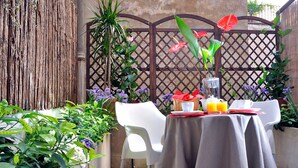 A table set for two with a tablecloth, two chairs, and a basket of fruit. - Best Pantheon B&B (Rome)