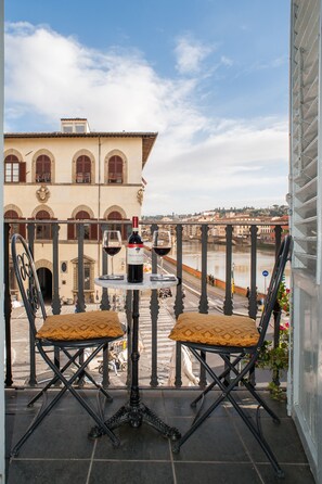 A balcony with two chairs and a table, a bottle of wine, and a glass of wine. - Residenza Vespucci (Florence)