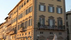 Un edificio de varios pisos con estilo arquitectónico clásico, que cuenta con balcones y una estatua en su fachada.