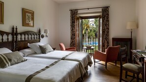 Une chambre d’hôtel avec deux lits, un bureau, une chaise et une vue sur la piscine.